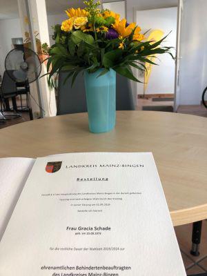 Ernennungsurkunde für Gracia Schade mit Blumenstrauß