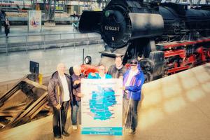 Reisegruppe NIemand vor historischer Lok und Reiseplan in Leipzig