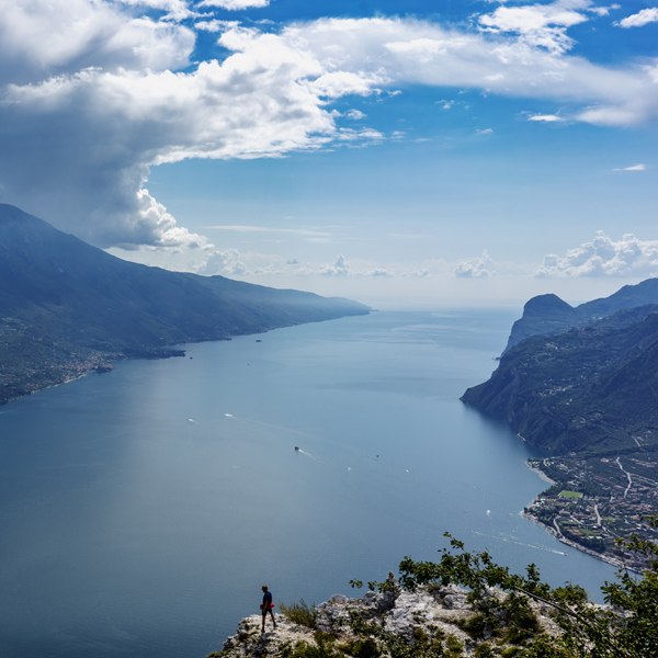 Eine kleine menschliche Figur und im Hintergrund die Gewässer von dem Gardasee