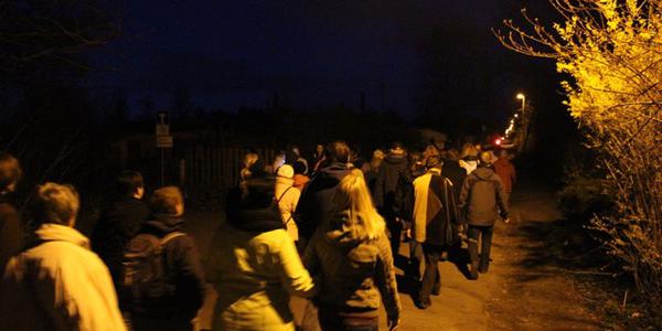 Foto zeigt Menschen abends auf dem Gedenkweg