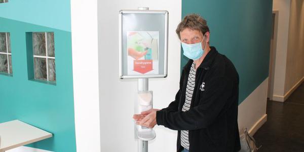 Hygiene bleibt weiterhin sehr wichtig - Person mit Gesichtsmaske am Desinfektionsspender