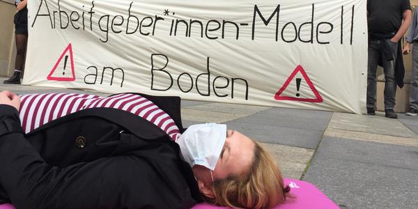 Frau liegt auf dem Boden vor dem Plakat