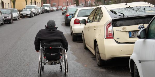 Foto zeigt Rollstuhlnutzer neben Taxi