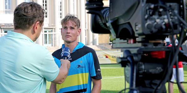Der Fußballer Taime Kuttig  vor Kamera und vom Reporter gehaltenen MikrofonMikrofon in einem Interview