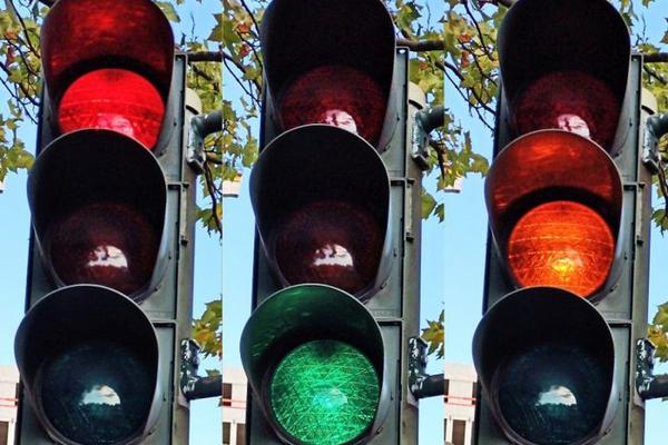 Drei Ampeln nebeneinander zeigen die Farben Rot, Gelb, Grün