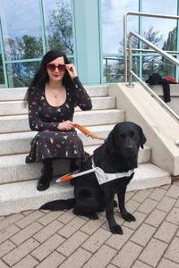 Jennifer Sonntag sitzt mit Führhund Paul auf den Stufen