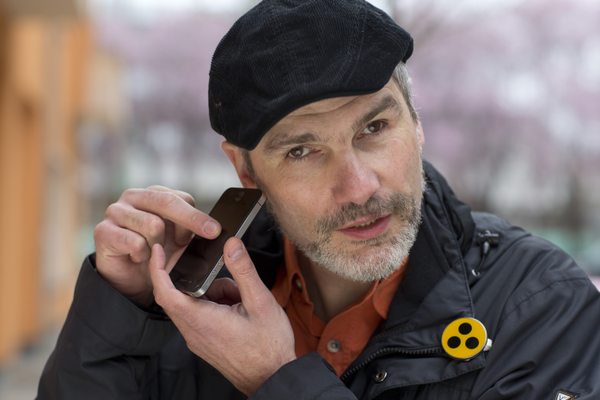 Blinder Mann hält sich ein Smartphone an das rechte Ohr
