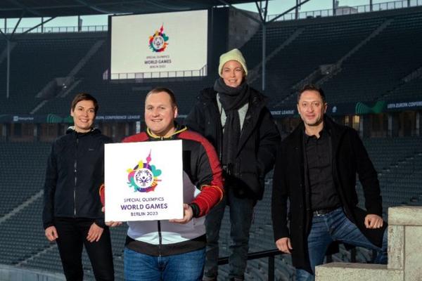 Foto von der Vorstellung des Logos für die  SOWG Berlin 2023. Vier Personen mit Logo in einem Stadion.