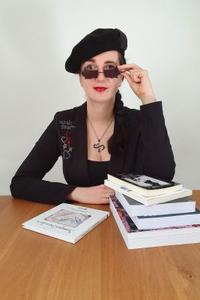 Jennifer Sonntag mit Mütze am Tisch mit Büchern vor sich
