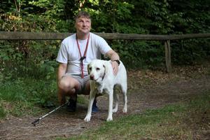 Per Busch mit Führhündin Peggy vor Holzgeländer im Wald