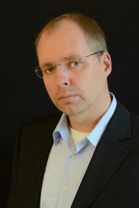Portrait von Prof. Dr. Torsten Schaumberg - Mann mit dunkler Anzugjacke und weißen, offenen Hemd