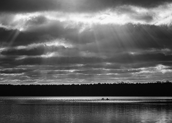 Zwei Angler im See. Die Sonne strahlt durch die Wolken