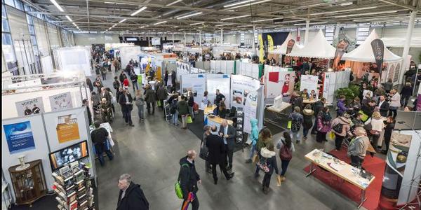 Foto zeigt Blick in eine Messehalle mit Exponaten und Besucern