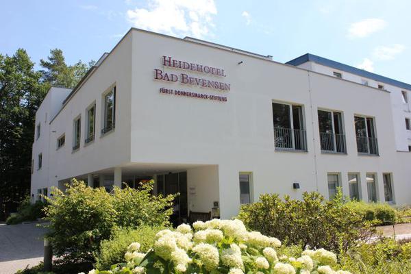 Weißes, zweigeschossiges Gebäude von Blumen und Bäumen umgeben
