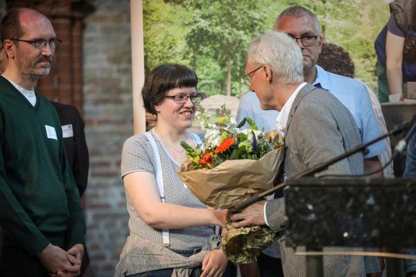 Junge Frau erhält Blumenstrauß bei der Preisübergabe