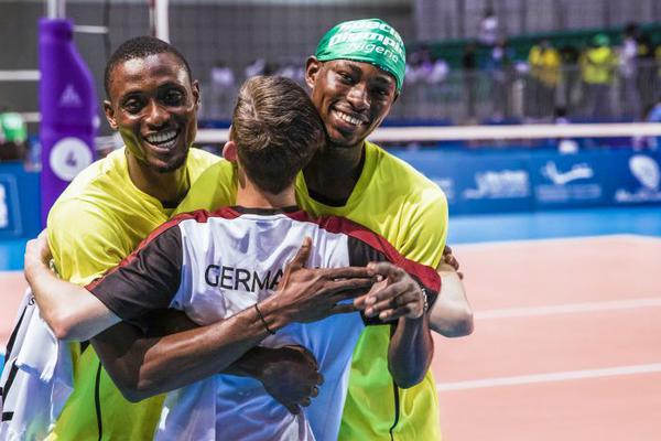 Volleyballer Fabian Henselmann und zwei Athleten aus Nigeria umarmen sich