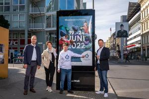 Vier Personen vor einem Plakat der Wall GmbH