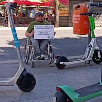 Alexander Ahrens mit Plakat vor E-Scootern