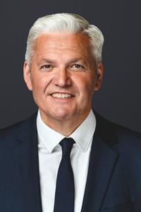 Portraitfoto von Hubert Hüppe im dunklen Anzug, weißem Hemd und dunklem Binder