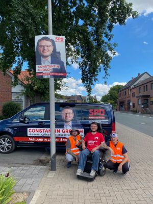 Constantin Grosch vor seinem Wahlkampfbus und Plakat