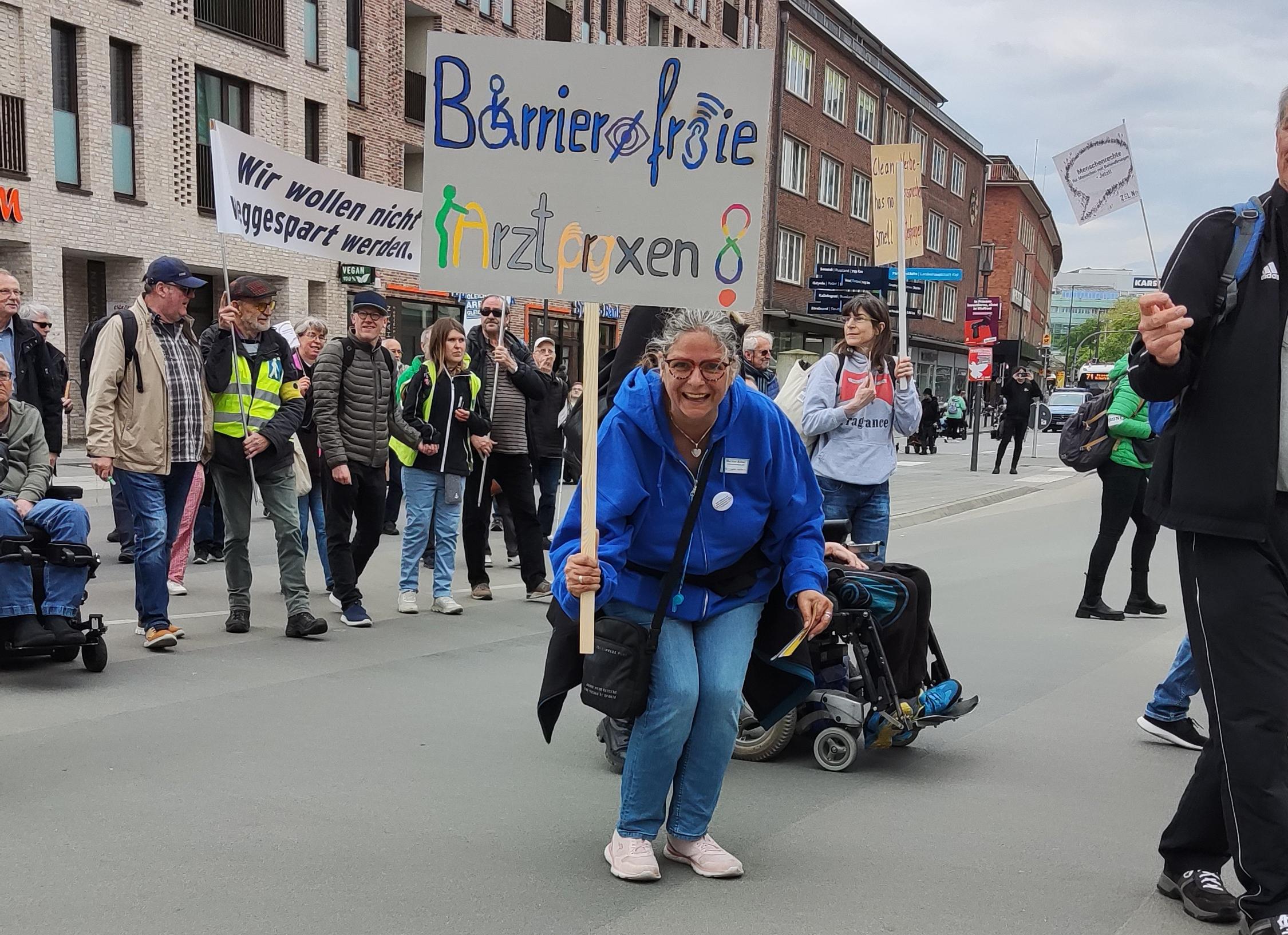 Frau mit Plakat Barrierefreie Arztpraxen