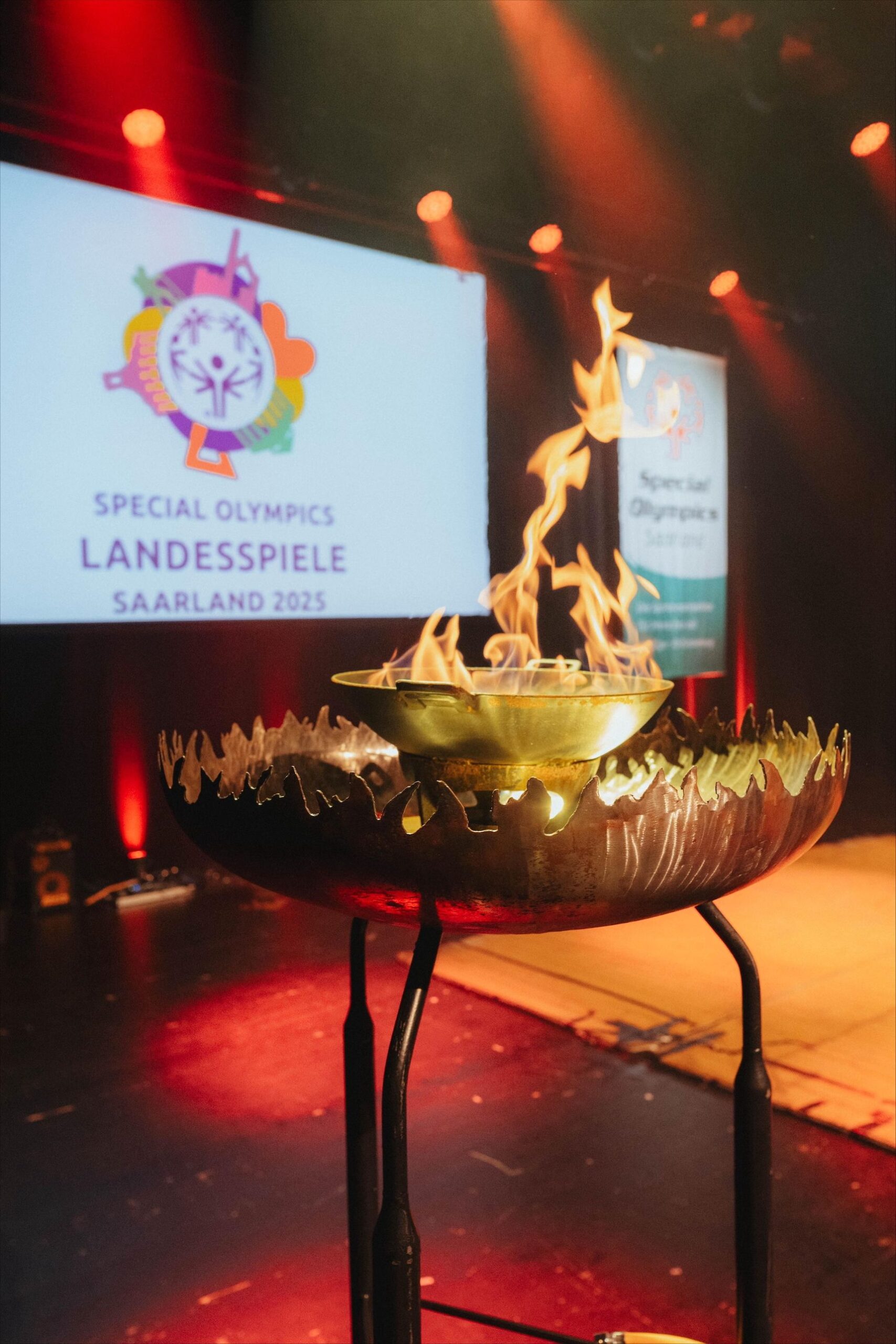 In einer Feuerschale brennt eine Flamme. Im Hintergrund ist das Loge der Special Olympics Saarland zu sehen