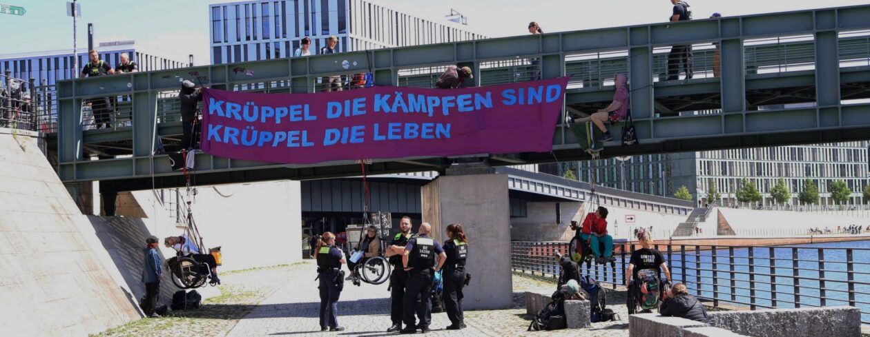 Abseilaktion gegen Kürzungen und für Barrierefreiheit mit Rollstuhl in Berlin mit Transparent