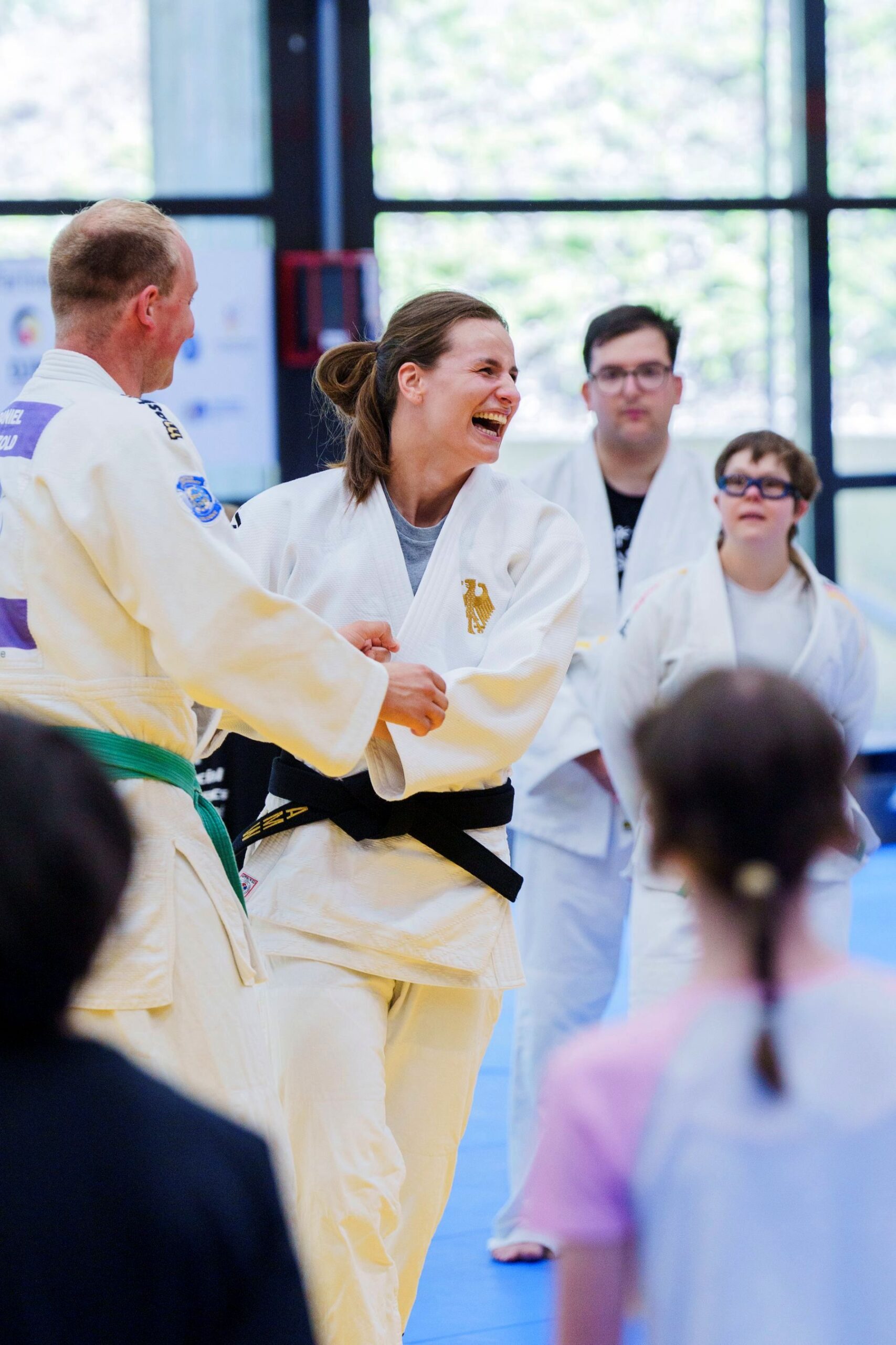 Sportlerinnen und Sportler in weißer Judo-Sportkleidung in fröhlicher Stimmung beim Trainieren