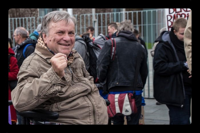 Bild von Ilja Seifert, lächelnd, mit erhobener Faust, von weiteren Demonstranten umgeben