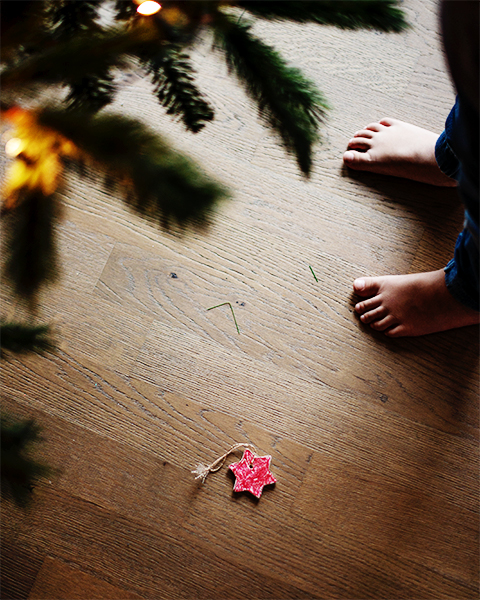 Kinderfüße neben einem Tannenbaum