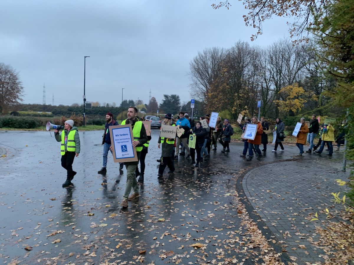 Demonstrationszug biegt in eine Straße ein. An der Spitze Demonstrantin mit Megafon