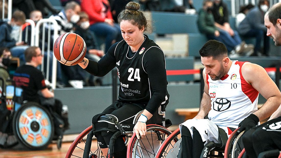 Zwei Basketballspieler kämpfen mit Rollstuhl um den Ball