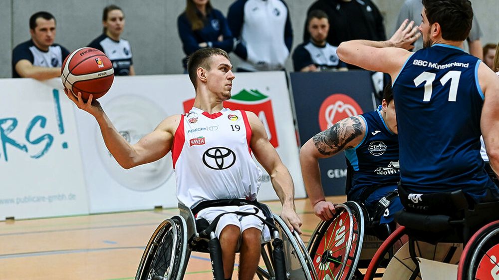 Basketballspieler in weißem und blauen Trikot mit Ball
