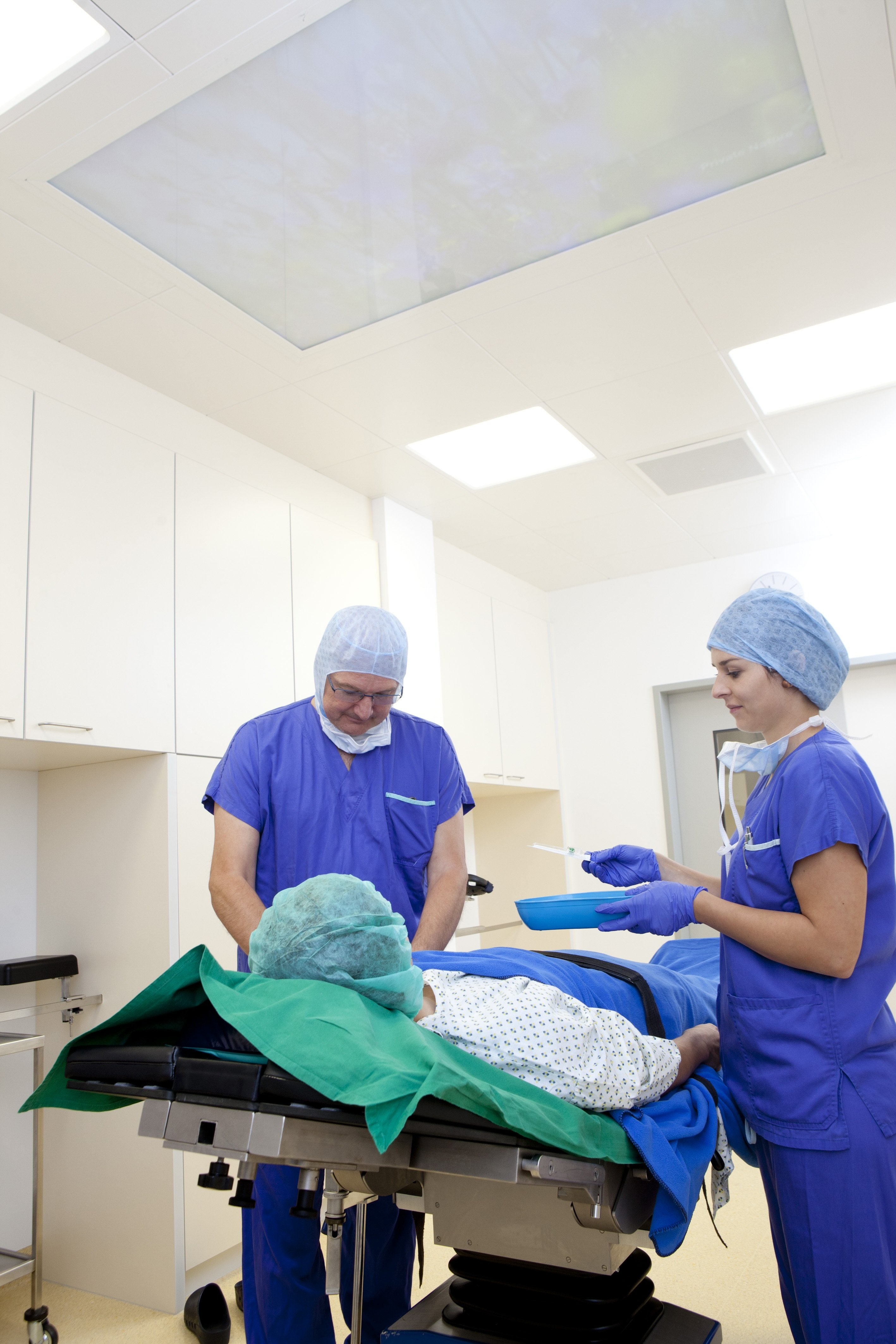 Zwei Mediziner in blauer Kleidung an einem Operationstisch mit einem Patienten