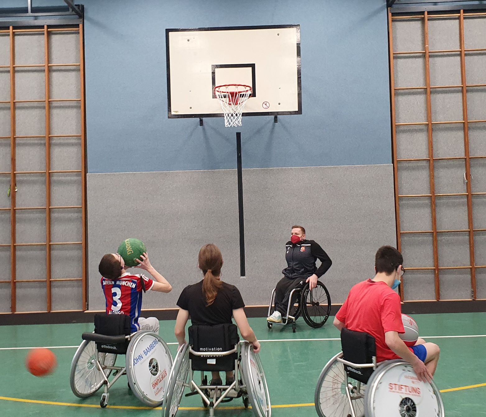 Fünf Personen mit Sportrollstühlen spielen Basketball