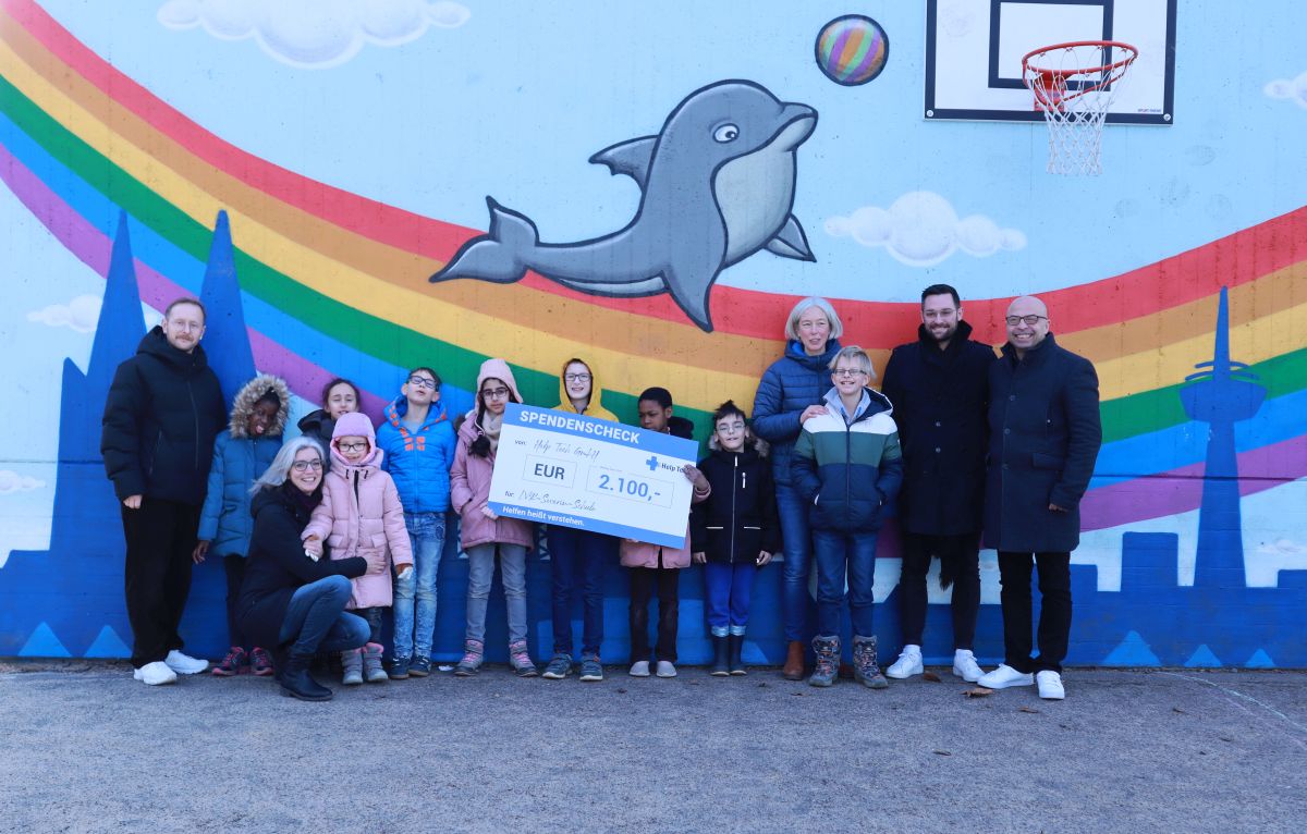 Gruppe von  Schülerinnen und Schülern mit Lehrern und Scheck über 2.100 Euro