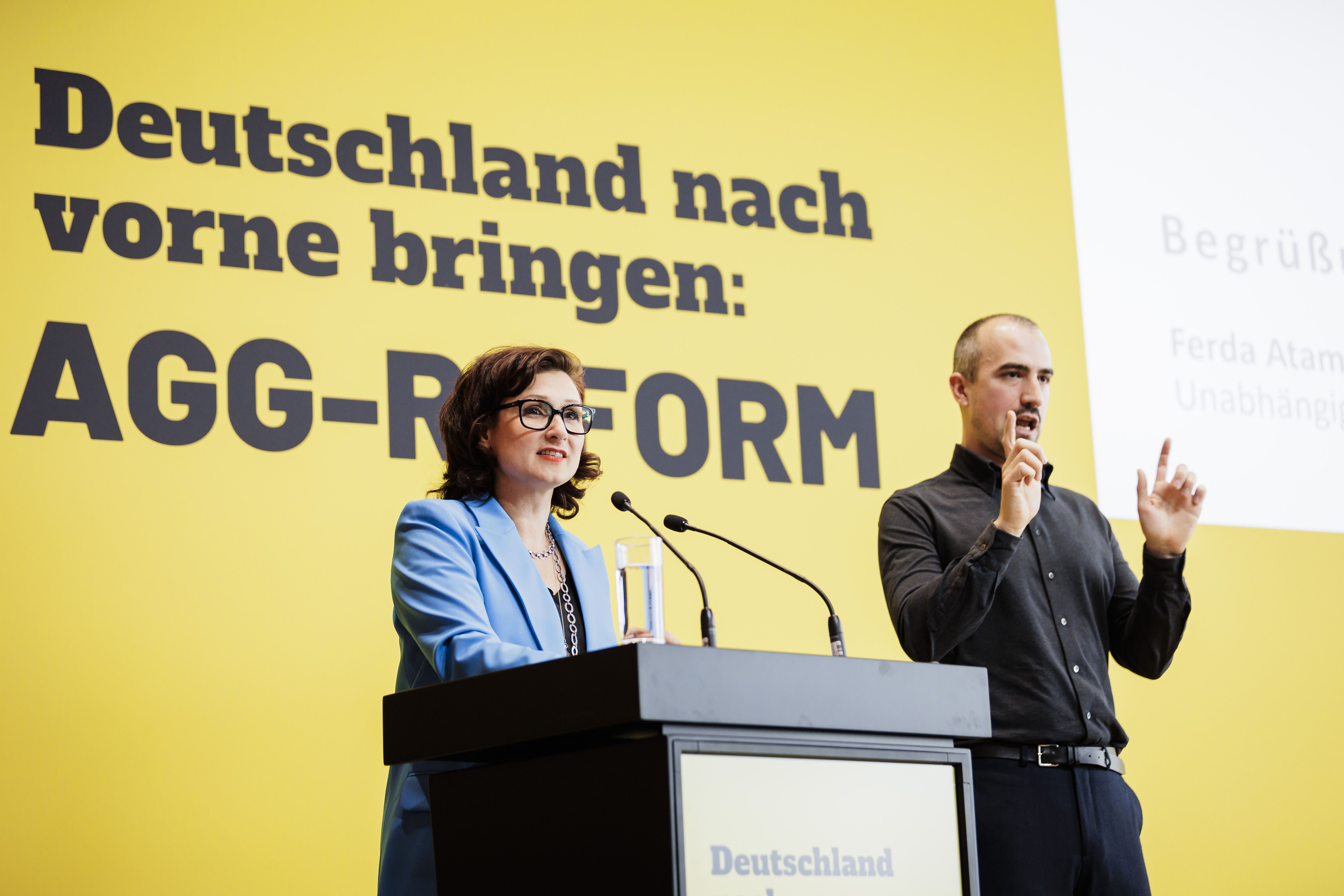 Ferda Ataman mit Gebärdendolmetscher vor Plakat