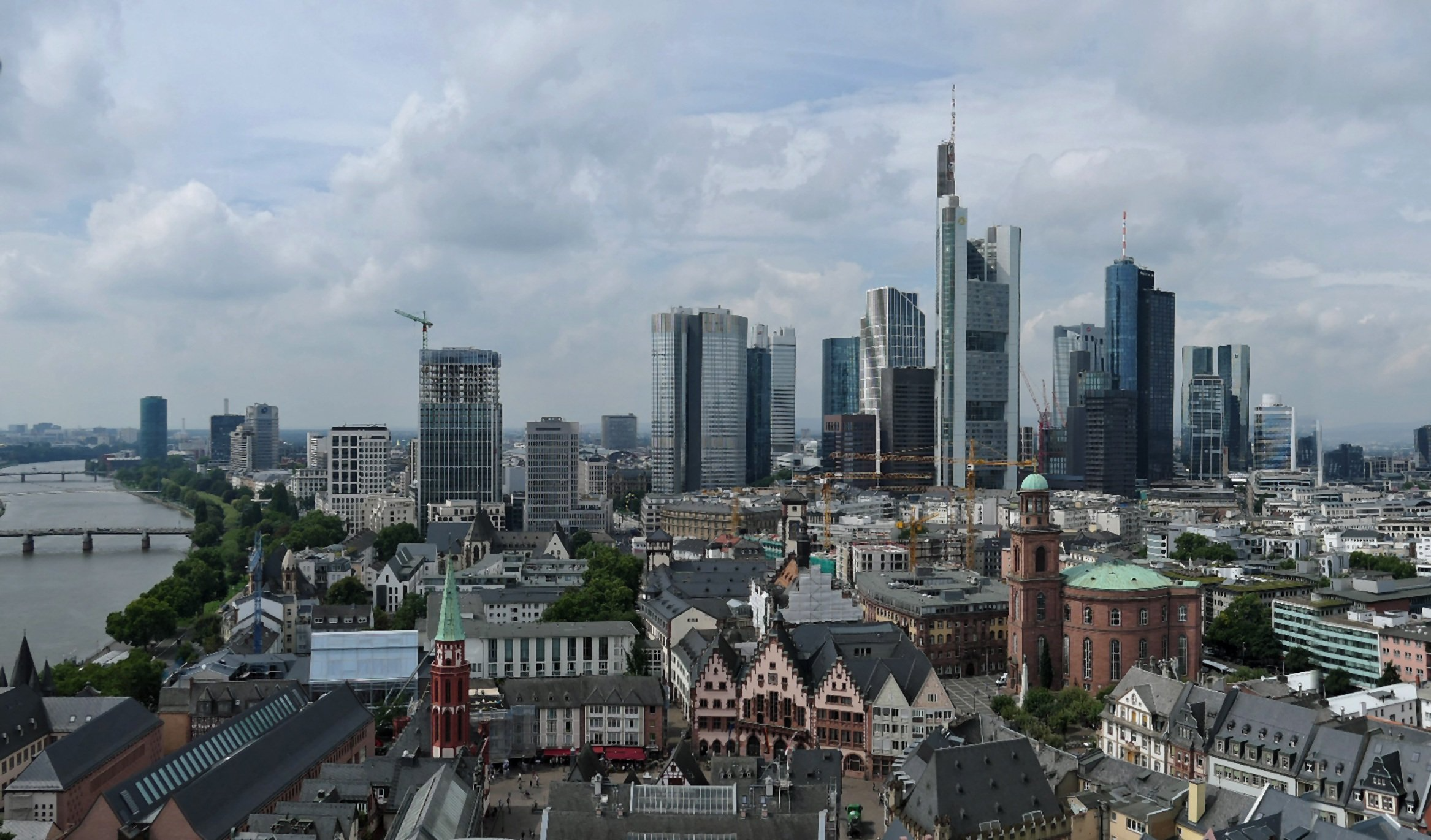 Bild einer Stadt mit Häusern und einer Kirche im Vordergrund sowie Hochhäusern im Hintergrund