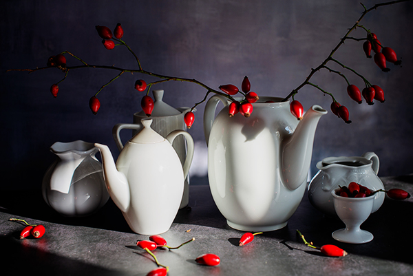 Hagebutten in weißen Kannen im Sonnenschein