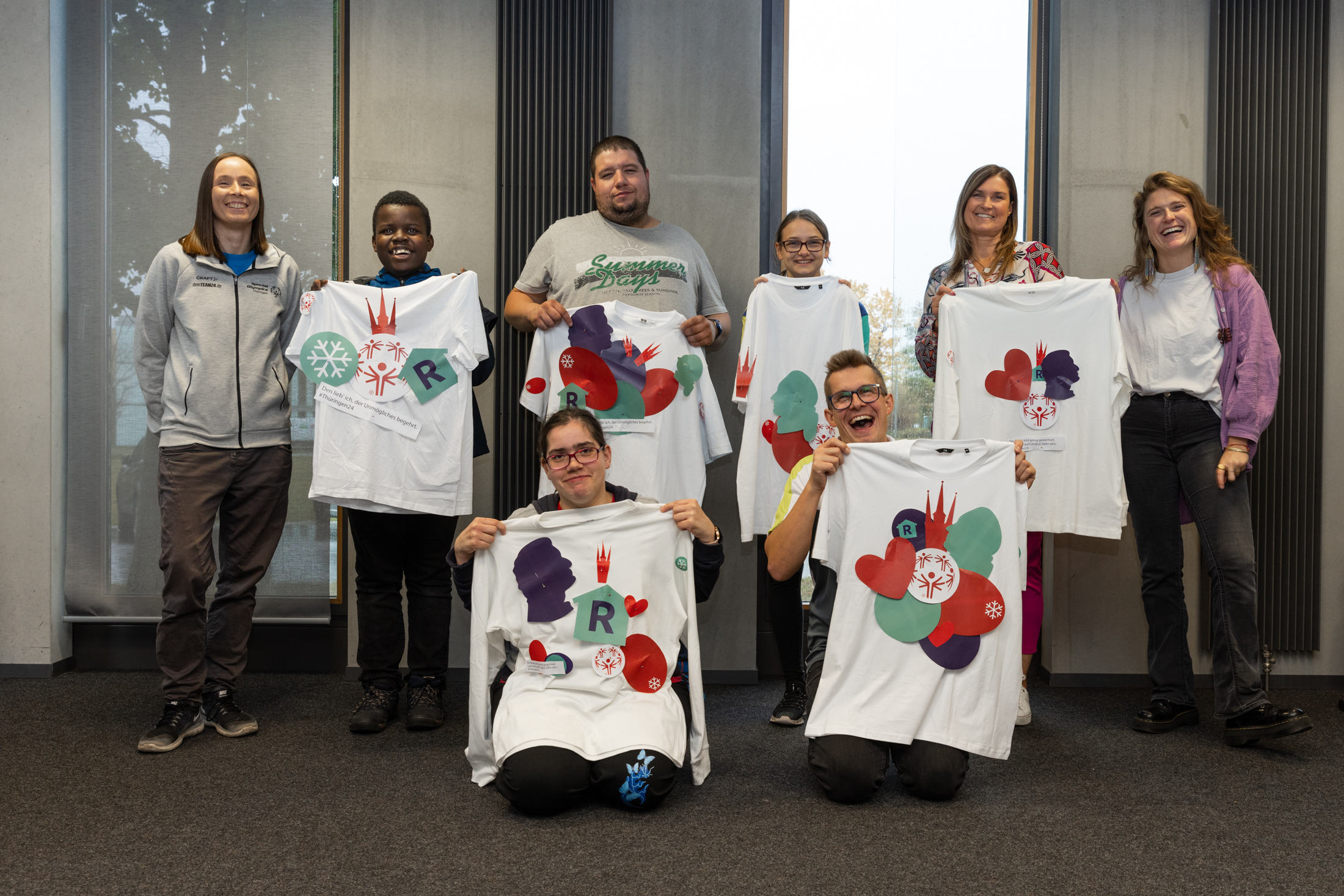 Gruppe von jungen Leuten, die bunte mit den Symbolen für die Nationalen Spiele bedruckte   T - Shirts zeigen
