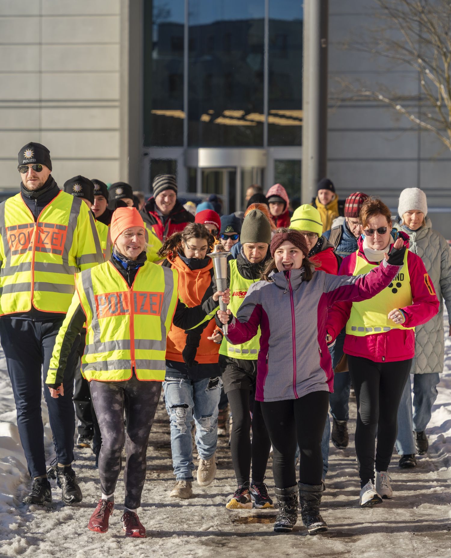 Gruppe von  Sportlerinnen  und Sportlern mit der Sportlerin mit der  Fackel