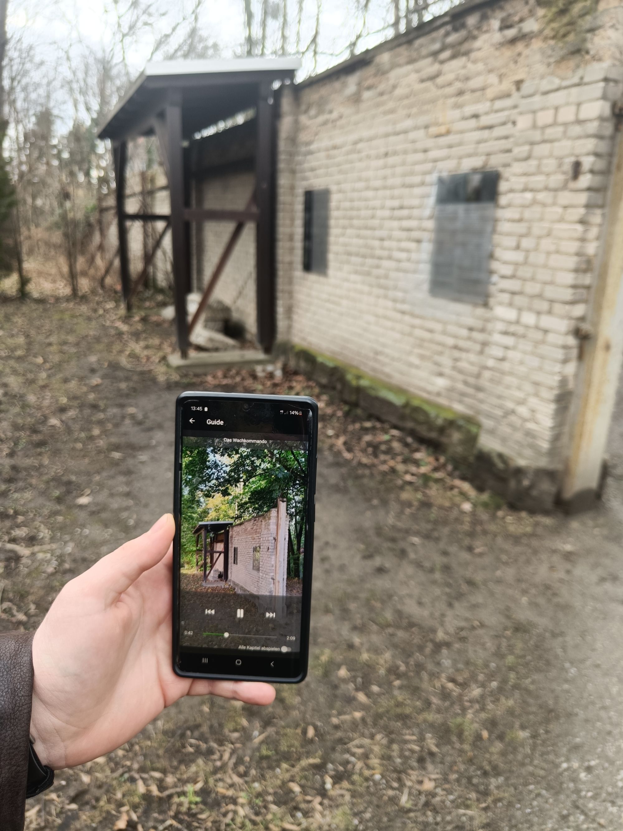 Hand mit enem Smartphone bei einem alten Flachbau