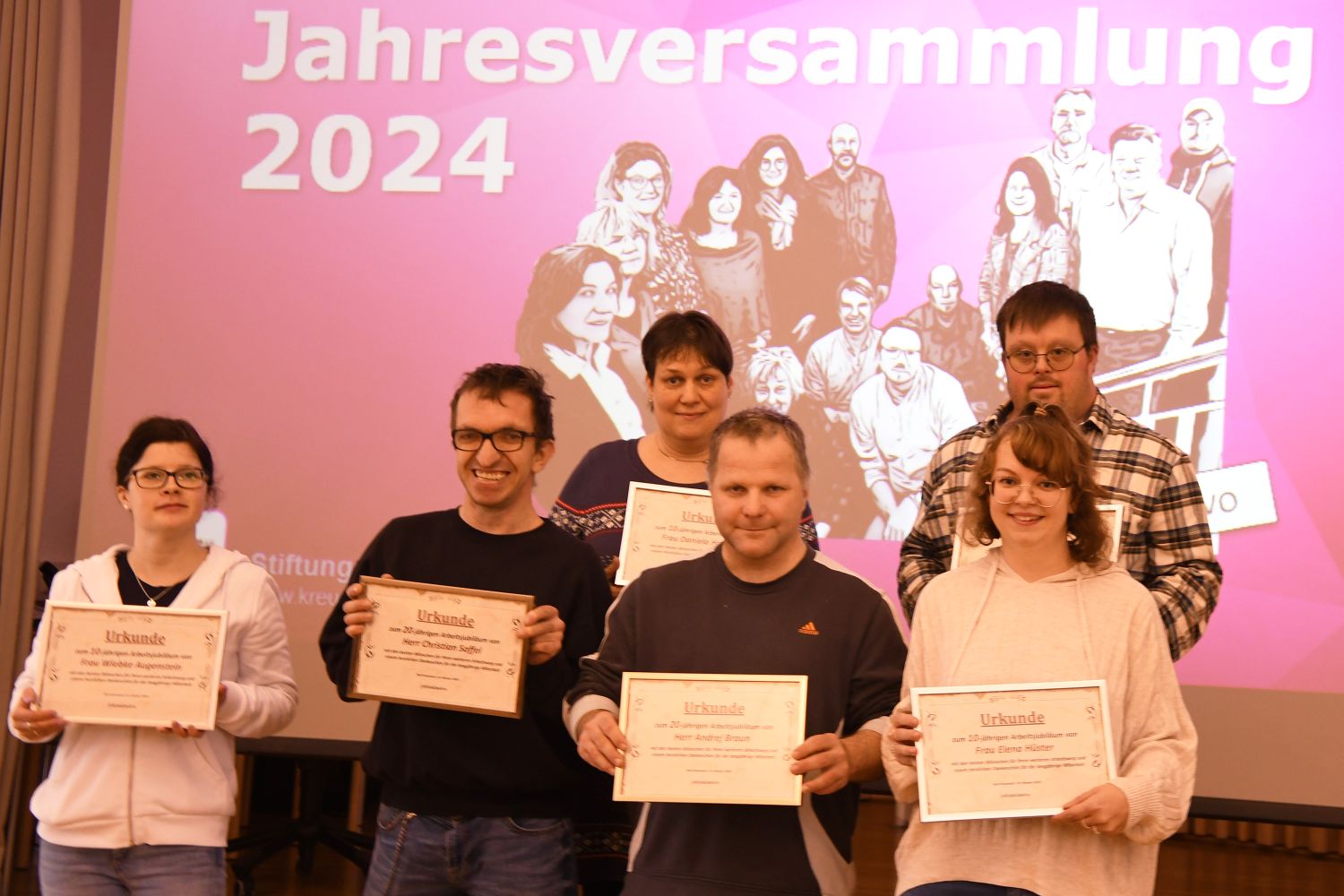Drei Frauen und drei Männer stehen mit Urkunden vor einer Wand mit  Aufschrift Jahreshauptversmmlung 2024