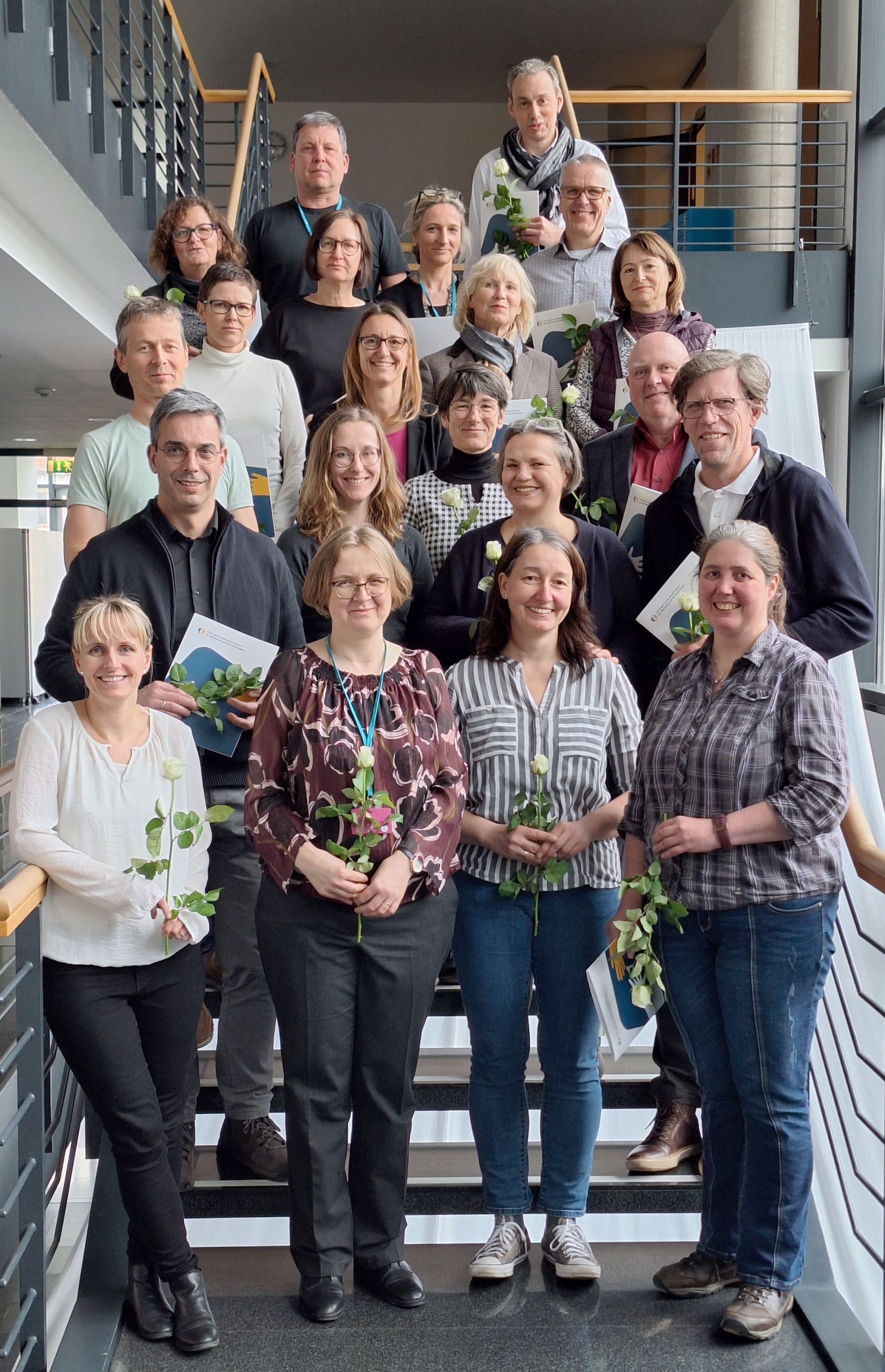 Männer  undFrauen in einem Gruppenbild auf einerTreppe