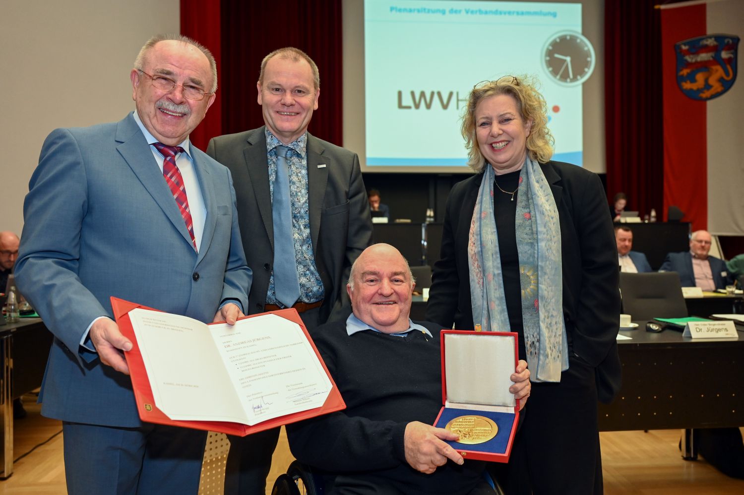 Dr. Andreas Jürgens im Rollstuhl sitzend dahinter stehend LWV-Präsident, Beigeordnetem und Landesdirektorin