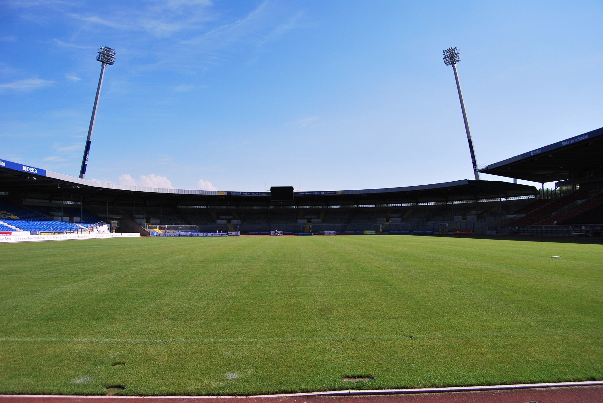 Blick in ein Stadion mit grünem Rasen und zwei Flutlichtanlagen