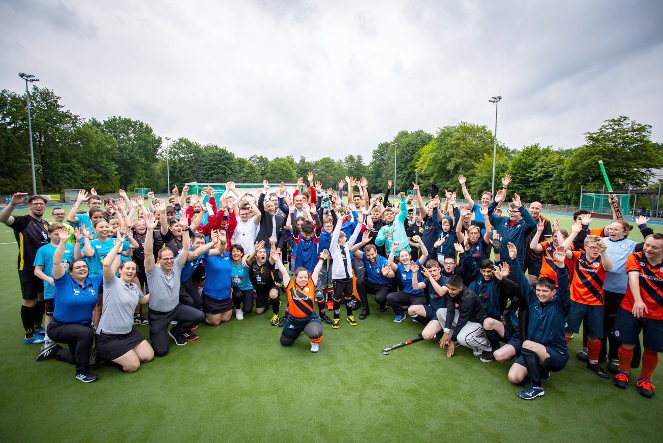 Viele Hockeysportler im Halbkreise auf einem Spielfeld