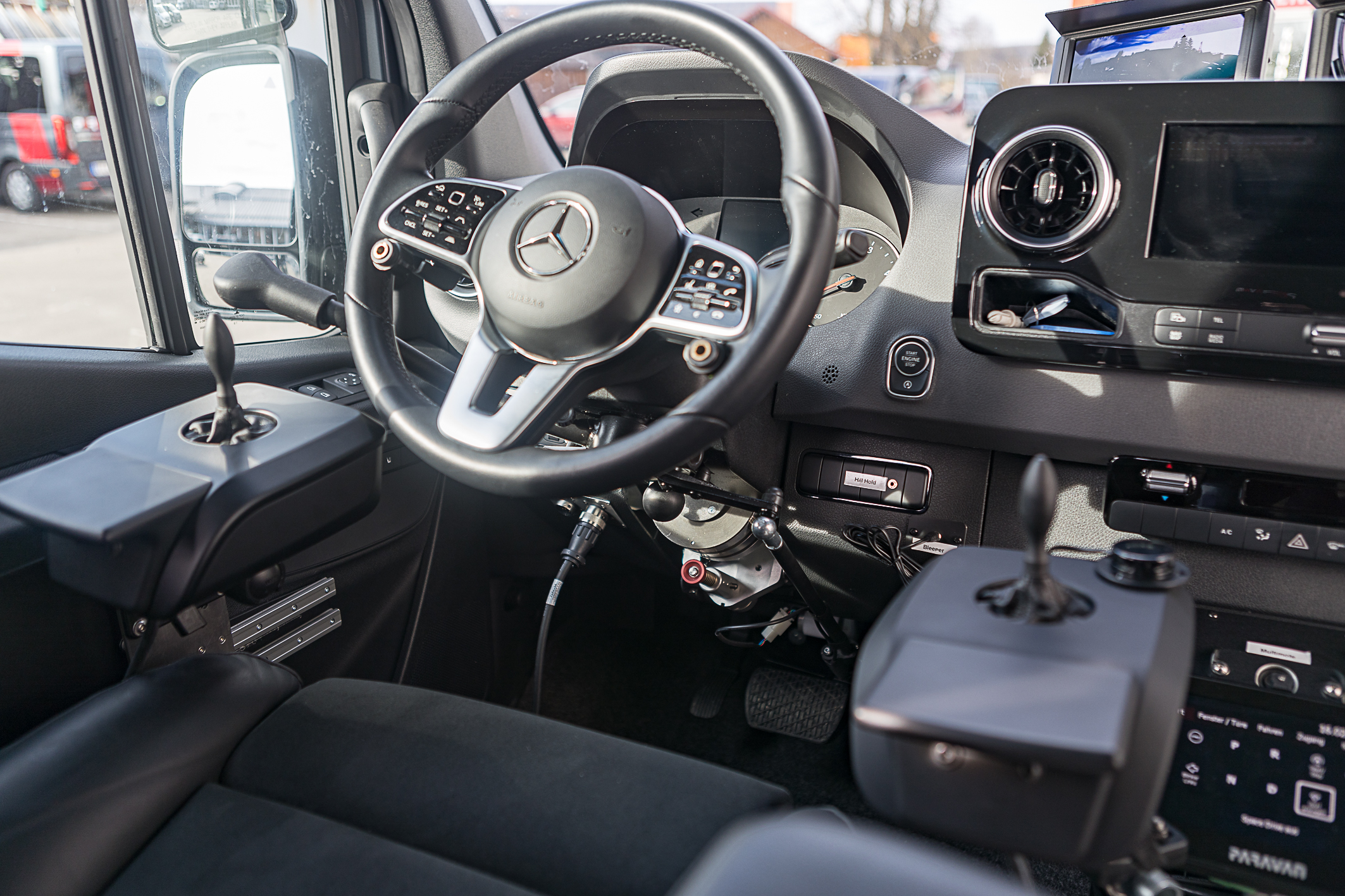 Fahrersitz eines Autos mit Lenkrad und Zusatzgeräten um ohne Beine Autofahren zu können
