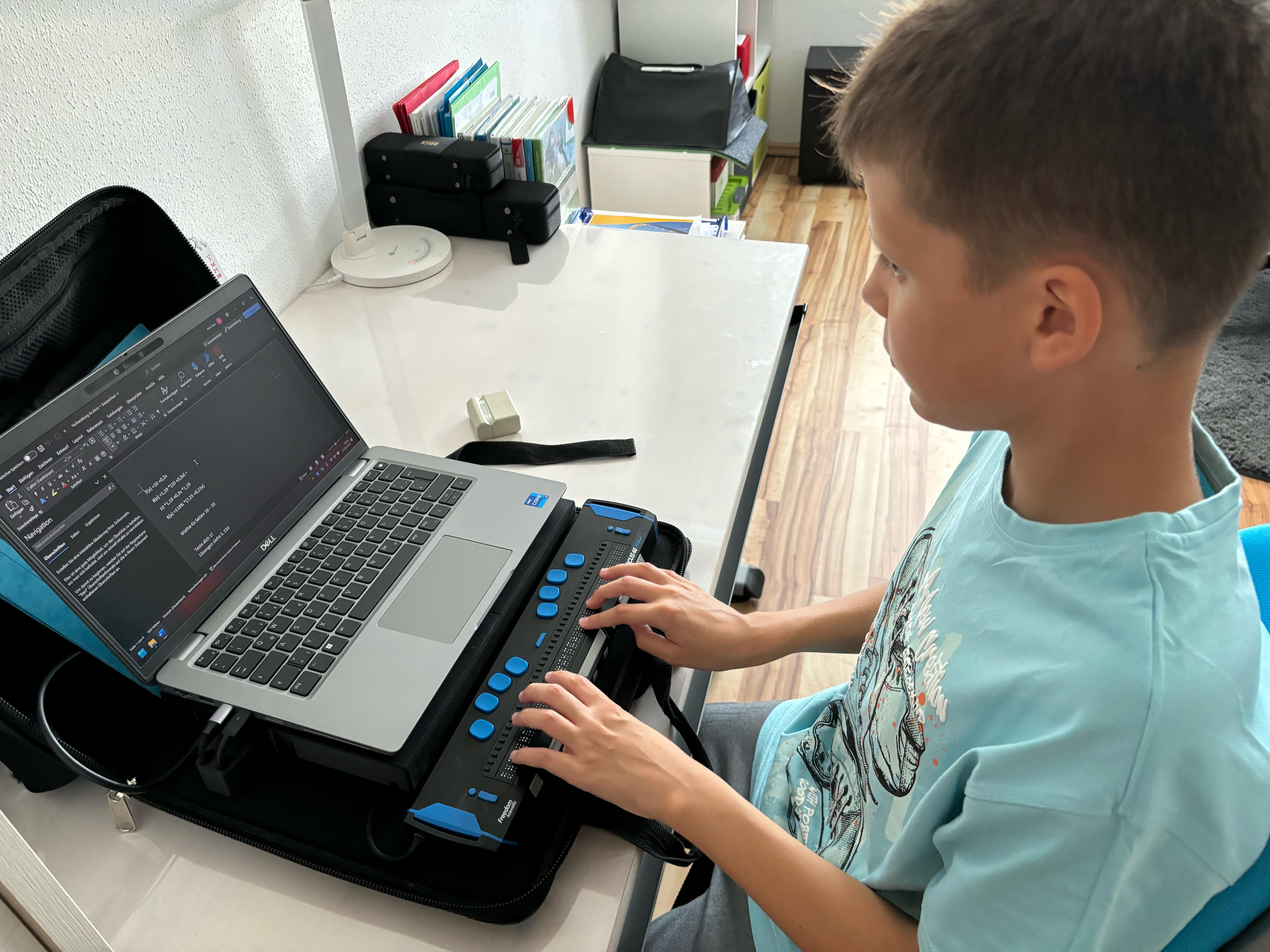 Ein Schüler sitzt an einem Tisch auf dem ein kleiner PC steht