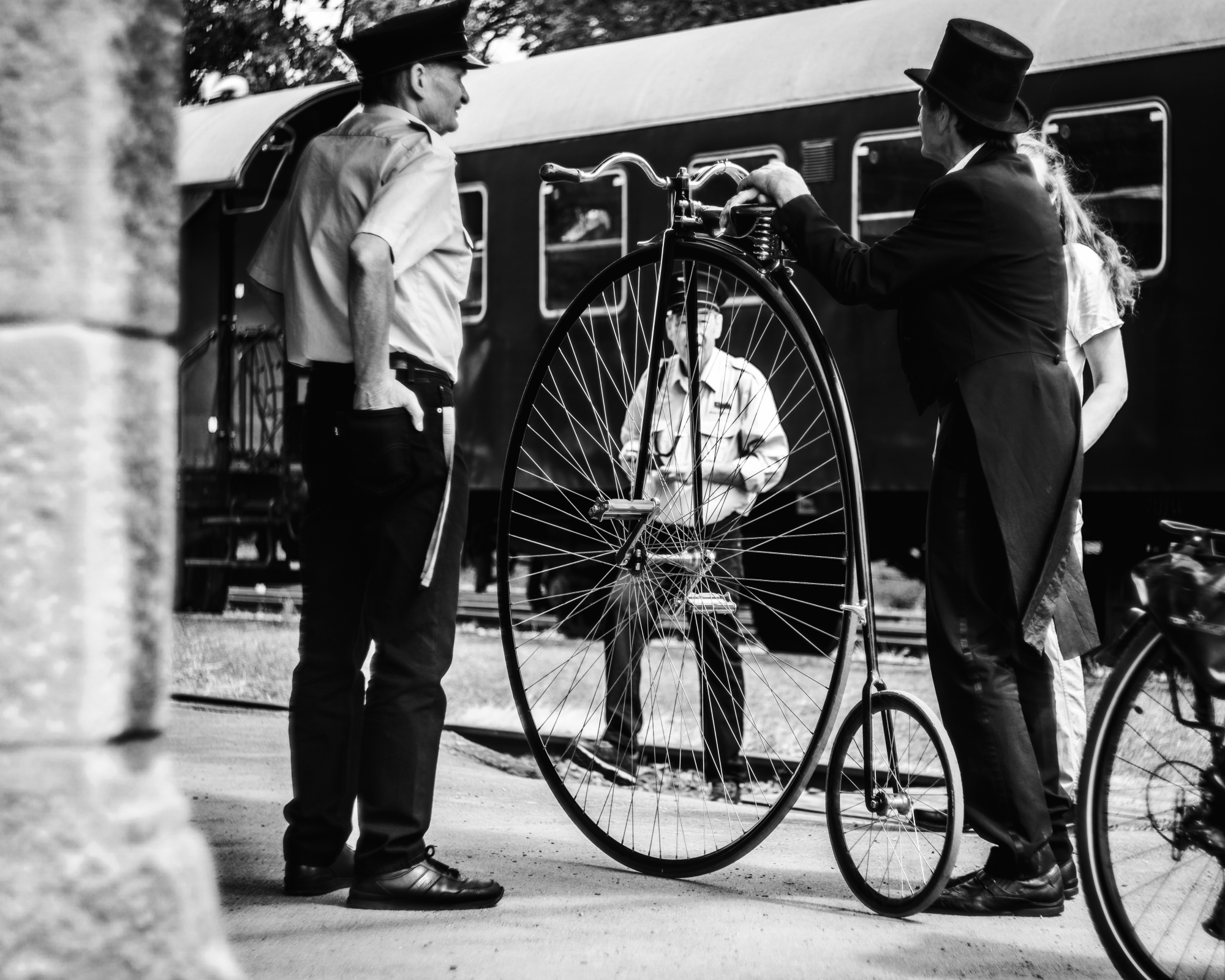 Ein Mann in einen Anzug und Zylinder aus dem Letzte Jahrhundert stzeht bei seinem Hoch-Rad. Schwarz Weiß Foto